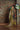 Woman in traditional attire standing against a brick wall with floral decorations.